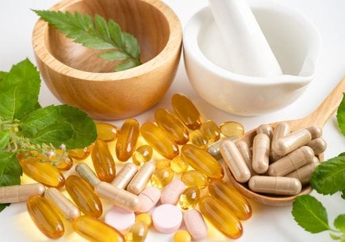 Mortar and pestle with herbs and supplement capsules representing complementary medication options in Surfers Paradise