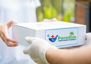 Paradise Compounding Pharmacy delivery box being handed to a customer