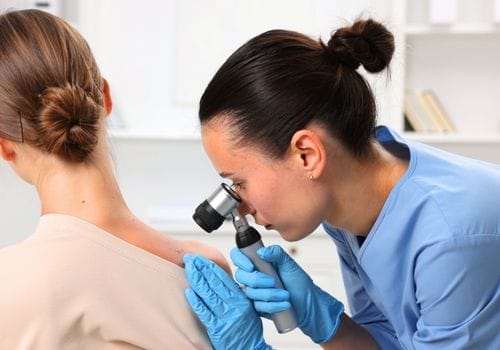 Doctor examining a patient back with a dermatoscope during a skin cancer check in Surfers Paradise